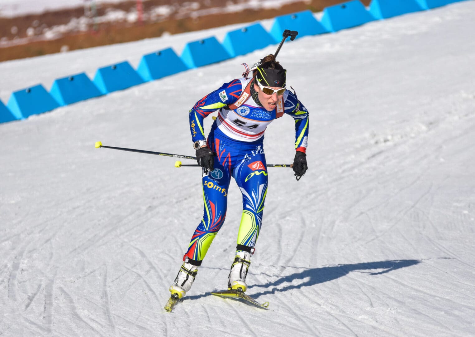 Biathlete racing on snow with rifle
