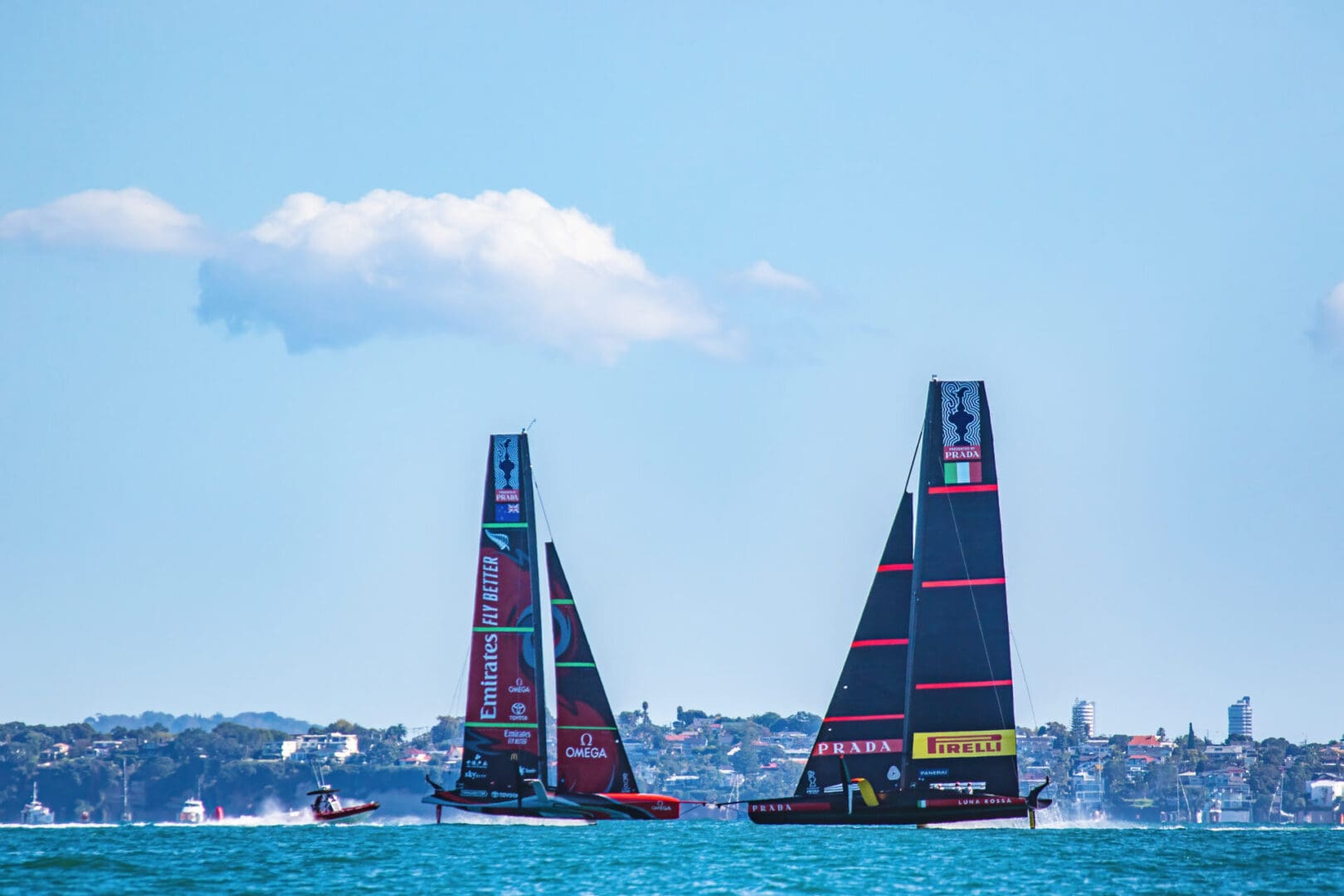 Two boats are sailing in the ocean near a city.