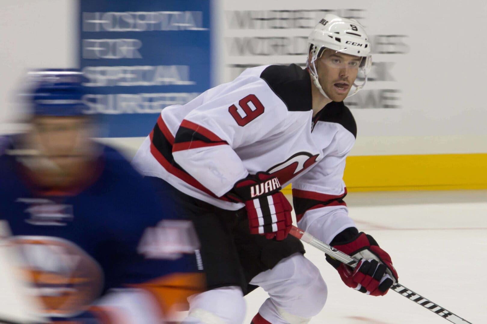 Hockey player in white jersey skating with puck