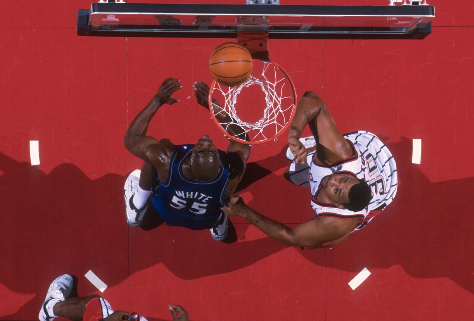 Two basketball players in a game are trying to block the ball.