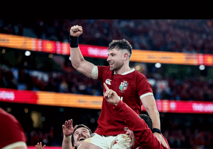 Rugby player celebrating victory on teammates' shoulders.