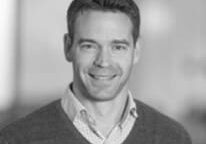 A man in a sweater and shirt smiling for the camera.