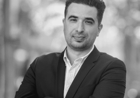 Man in a black suit with crossed arms.