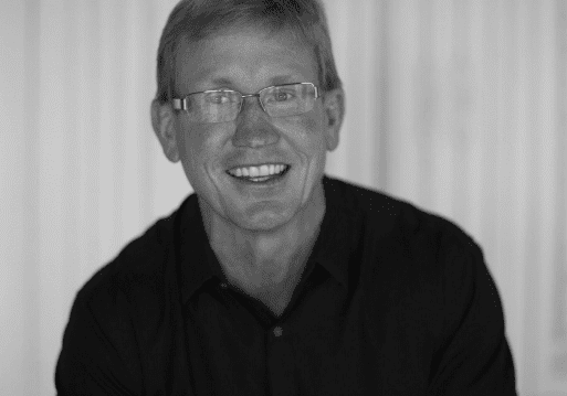 Smiling man wearing glasses in black shirt.