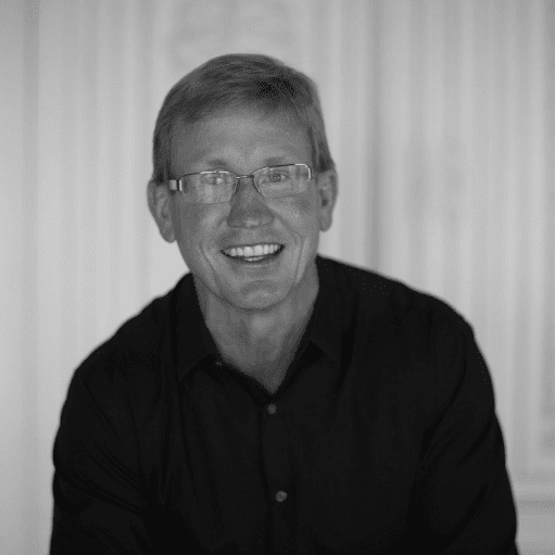 Smiling man wearing glasses in black shirt.
