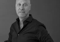 A man in black shirt standing next to wall.